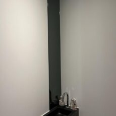 Espejo largo y estrecho encima del lavabo. Pegado en el cuarto de aseo
